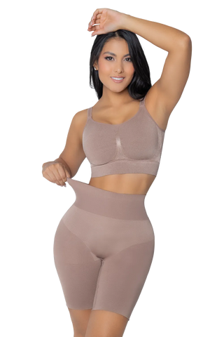 A woman is wearing a pair of beige, high-waisted, seamless shapewear shorts with a push-up effect by Jackie London